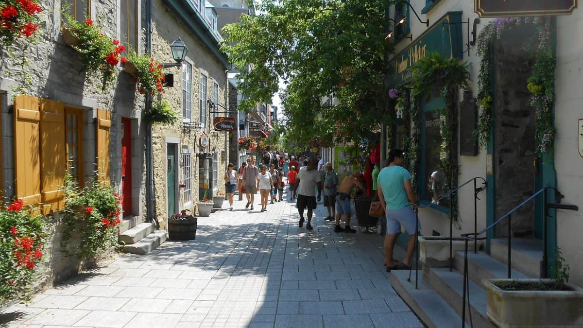 tourists walking on Narrow cobblestone street lined with historic buildings and charming shops in Quebec City, Canada