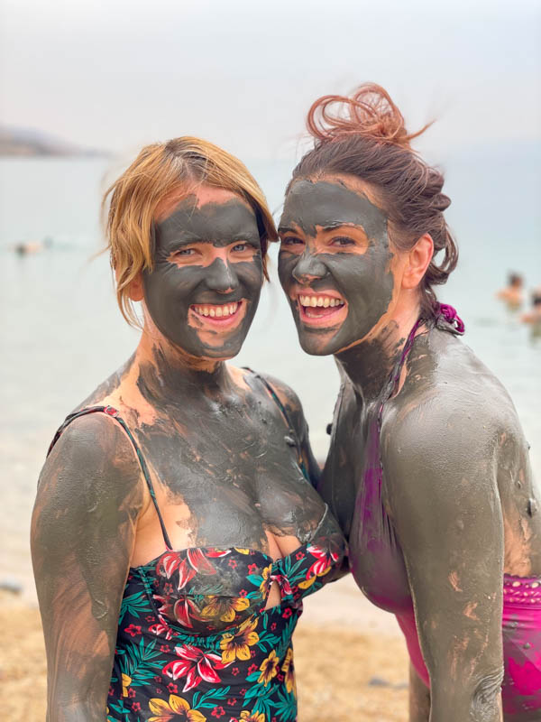 two girls covered in mud at the dead sea in jordan