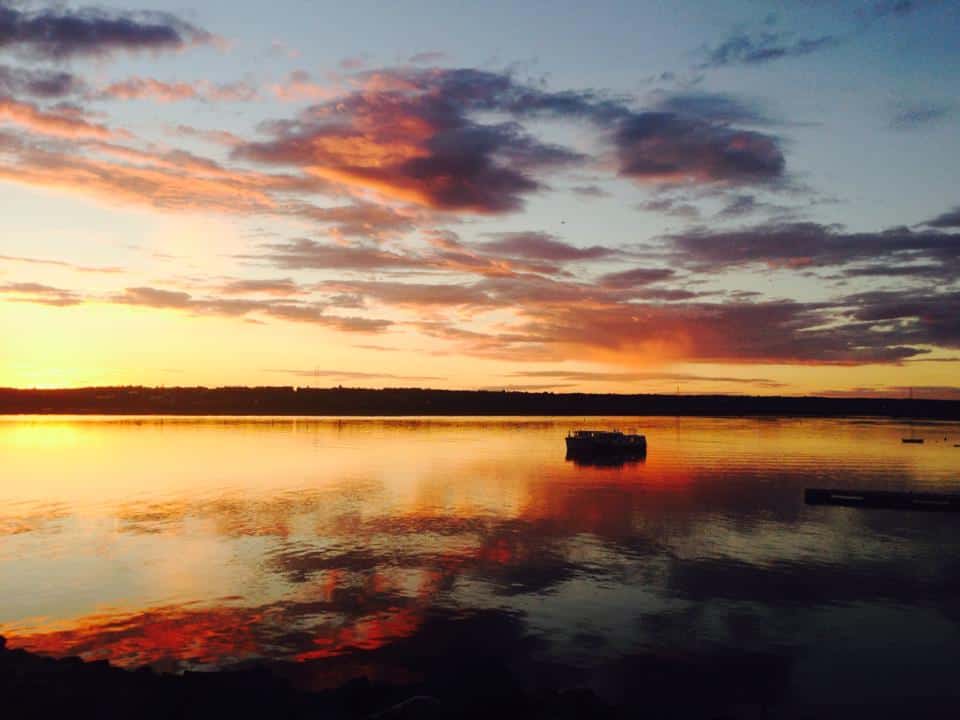 A sunset over a body of water with a boat in it, captured during an east coast Canada road trip.