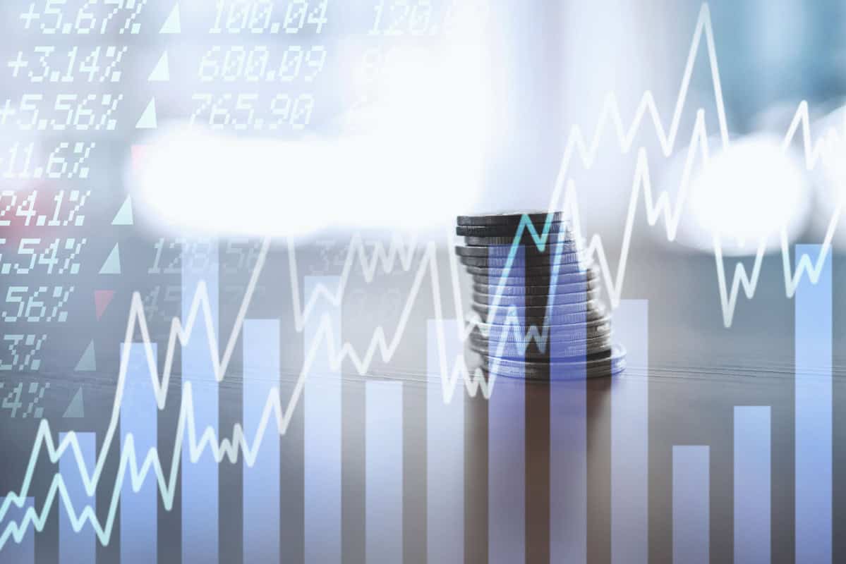 A stack of coins is overlaid with stock market graphs and numerical data, representing financial growth and investment trends.